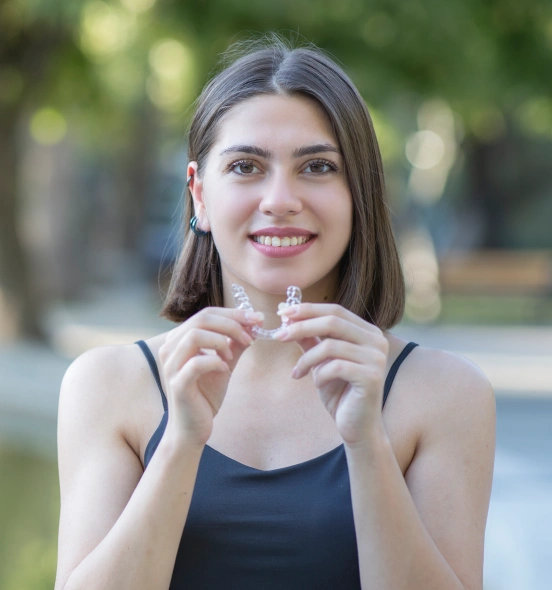 Young woman holding clear aligner trays for orthodontic treatment at TRU Dentistry SoCo in South Austin, TX